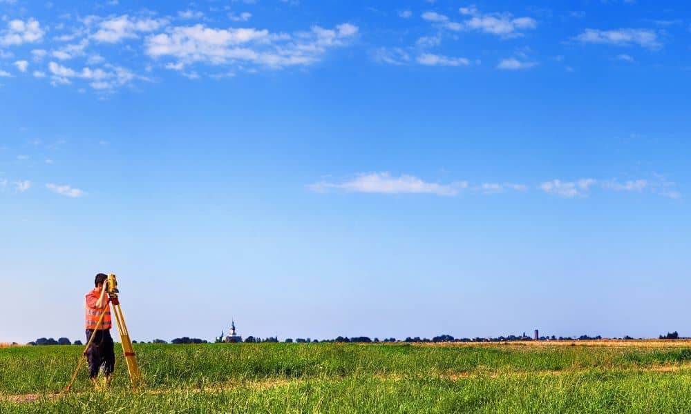 Land surveyor using gps under clear sky - ALTA SURVEY Ohio Land surveyor using GPS equipment in an open field under a bright blue sky