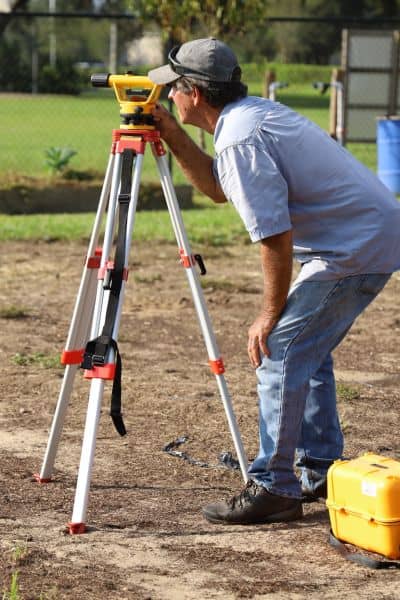 Land surveyor marking property boundary - ALTA SURVEY Ohio Licensed land surveyor using professional equipment to mark property boundaries during a boundary survey