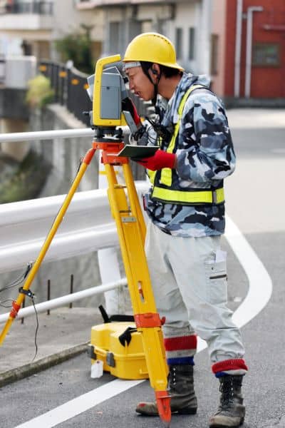 Licensed land surveyor using a total station to measure property boundaries and update site data for an ALTA Title Survey