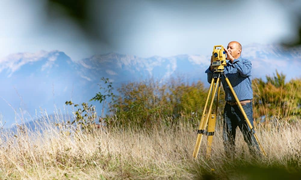 A land surveyor using GNSS equipment in the field to collect accurate data for mapping and land surveying projects
