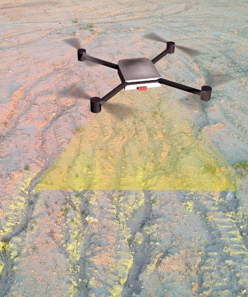 Drone performing an aerial survey while a surveyor monitors the scan on uneven land