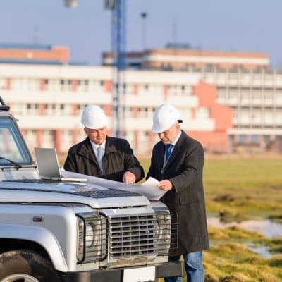 Construction surveyor reviewing site plans to confirm layout accuracy before excavation