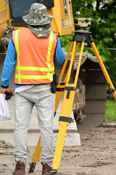 Licensed surveyor measuring residential property - ALTA SURVEY Ohio Licensed land surveyor taking measurements with a tripod and survey tools on a residential property, illustrating a professional property survey