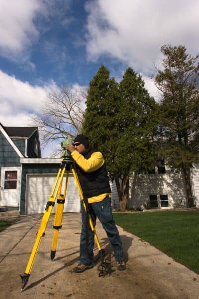 Land surveyor measuring a residential property for a land survey for fence placement