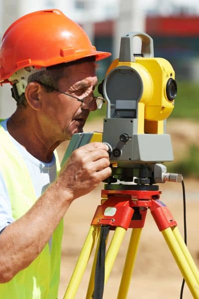 Surveyor using professional equipment to measure a residential property during a site visit
